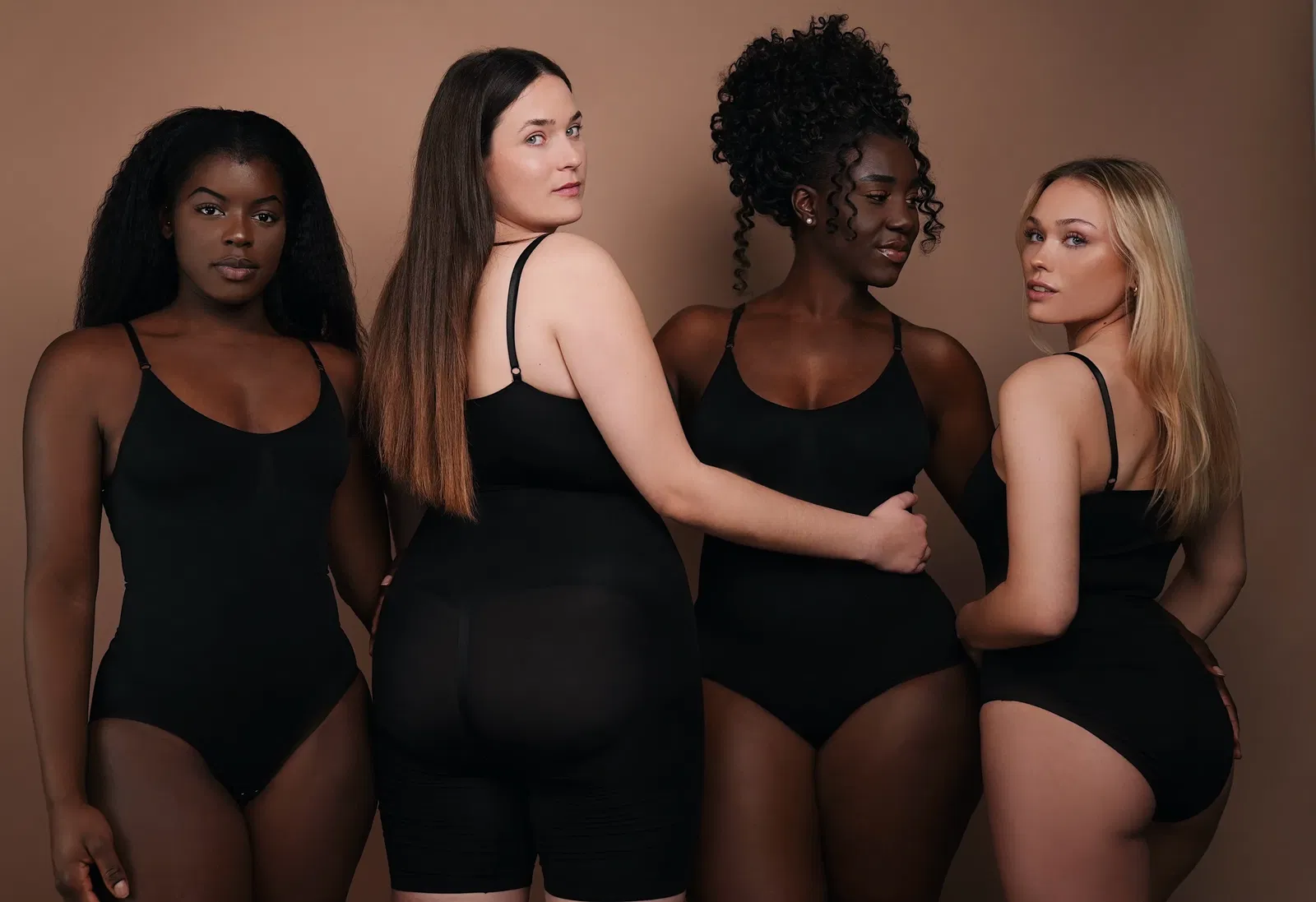 Vier Frauen in schwarzen Bodys vor neutralem Hintergrund, die Vielfalt und Eleganz von Figur formender Mode präsentieren. Vier Frauen in schwarzen Bodys vor neutralem Hintergrund, die Vielfalt und Eleganz von Figur formender Mode präsentieren.
